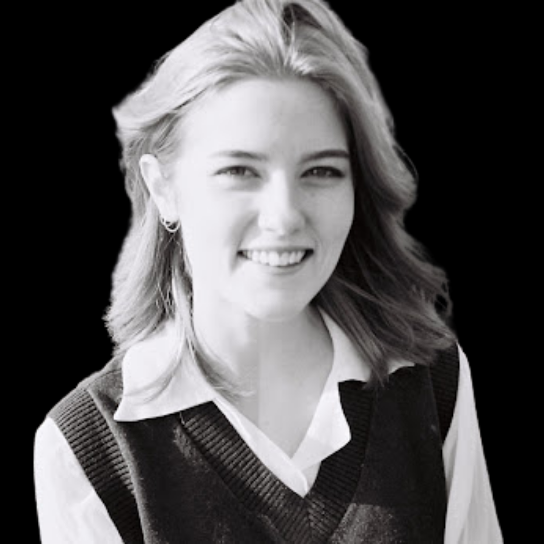 A black and white image of Pearl Kennedy - Pearl is wearing a white shirt with a dark vest and is smiling.